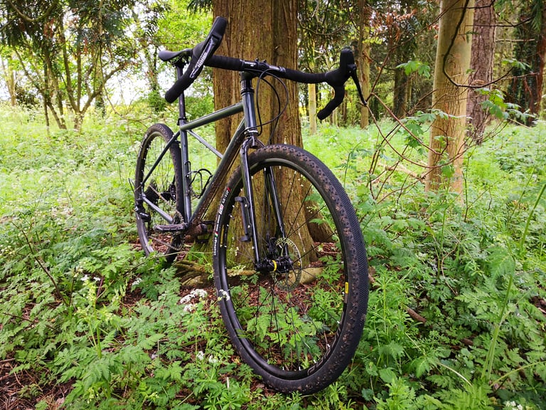 BiViBIKES Bunker steel frame with Ritchey bars and Mavic wheels, parked among trees and wild flowers.