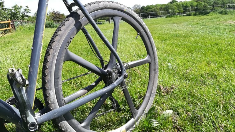 Close-up of the Merit Windmill rear wheel on the Mason Bokeh, five carbon spokes and a dusty gravel tyre in view.