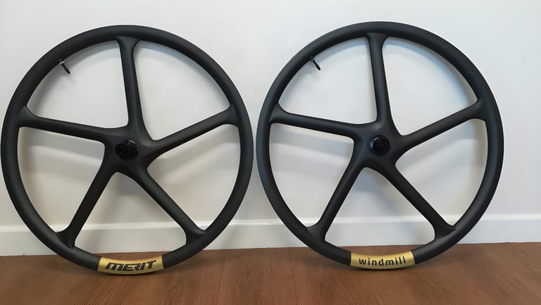 Merit Windmill carbon wheels, front and rear, showing the five-spoke monocoque design and gold Merit rim label.
