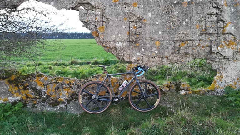 Mason Bokeh with Merit Windmill wheels leaning against a lichen-covered concrete ruin, fields behind.