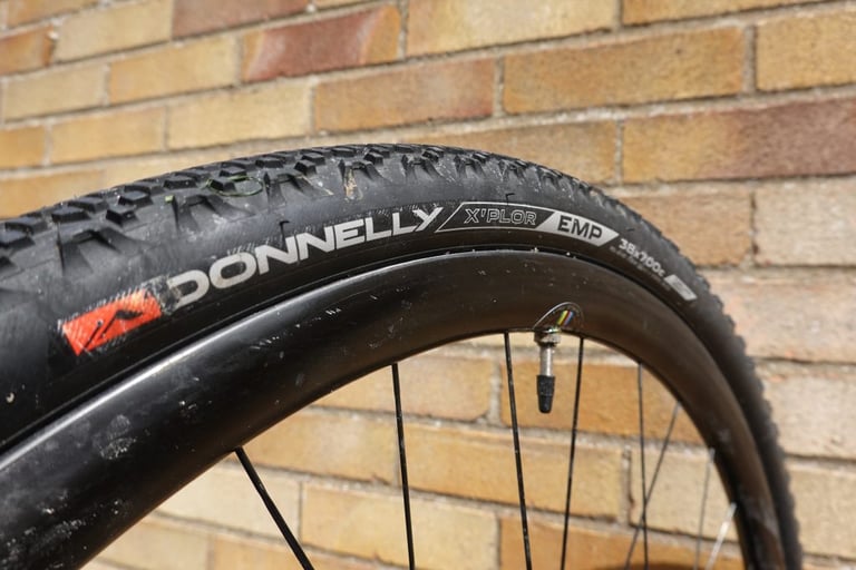 Sidewall of a Donnelly X'Plor EMP 38x700c after three months of testing, lightly scuffed, against a brick wall.