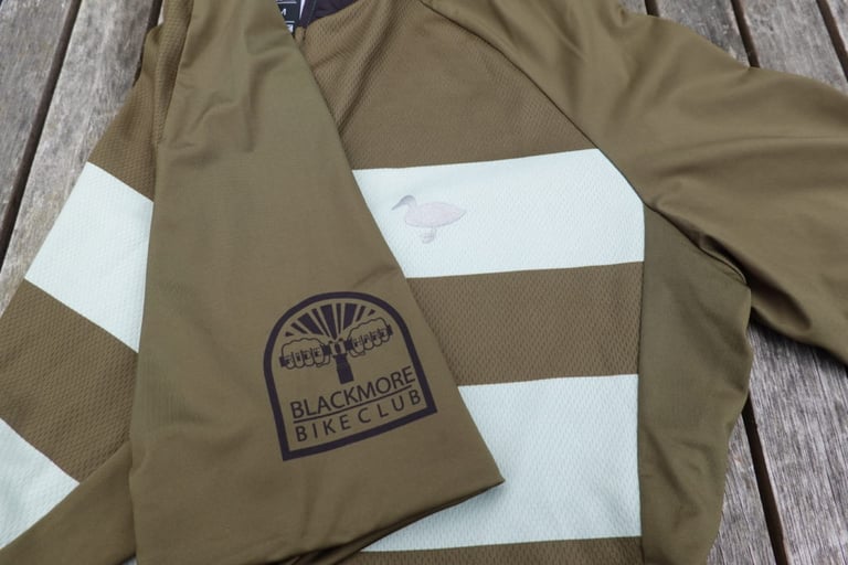 Sleeve of the Cadet jersey with its printed Blackmore Bike Club badge, next to the duck logo on the chest stripe.