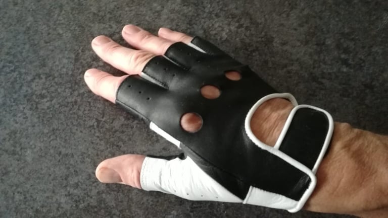 Back of a hand wearing a Galibier Ginettaccio black leather mitt with white piping and ventilation holes.