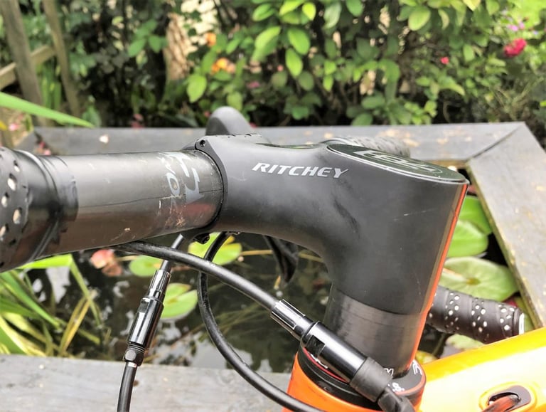 Ritchey WCS Chicane stem side-on on an orange Mason Bokeh, with no steerer bolts visible and a garden pond behind.