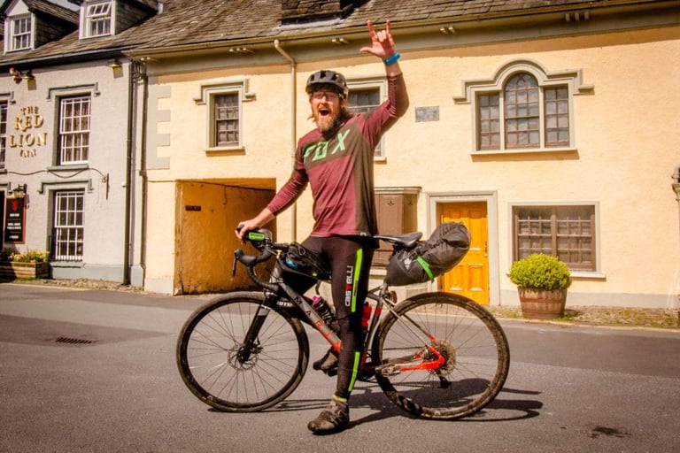 Tristan Taylor of Swinduro throws a rock salute astride his bag-laden Marin Gestalt outside a village pub on The Distance.
