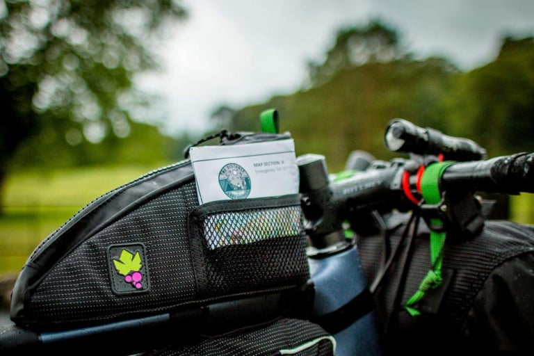 Miss Grape Node 2H top tube bag holding a printed Distance map card, mounted by the bike's bento bolts.
