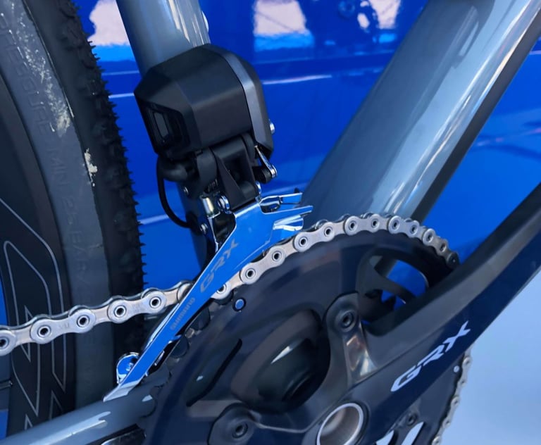 Shimano GRX Di2 front derailleur with its battery-powered motor unit sitting above a double chainring.