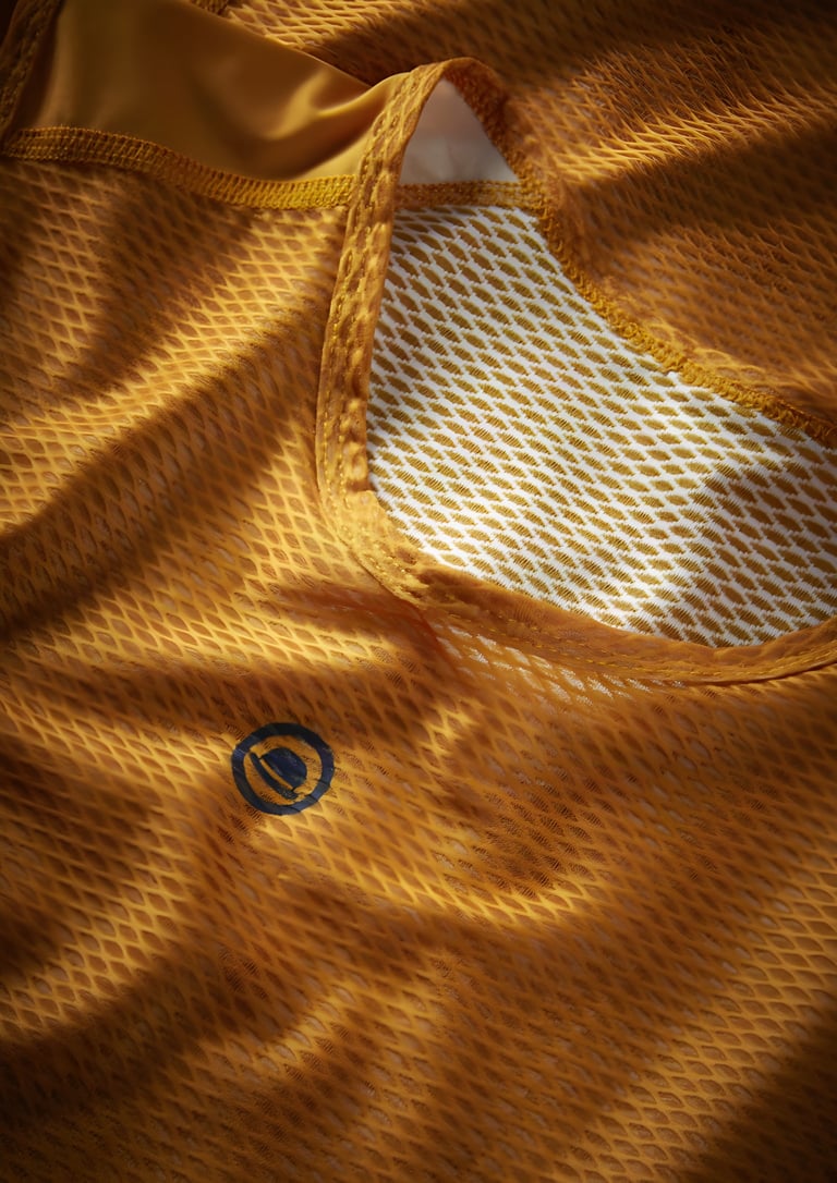 Close-up of the orange mesh fabric and neckline of the Chapeau sleeveless base layer.