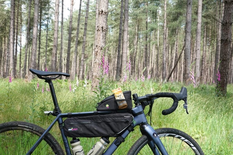 Lauf gravel bike carrying a Miss Grape Node 2H top tube bag above an Internode frame bag, among pines and foxgloves.