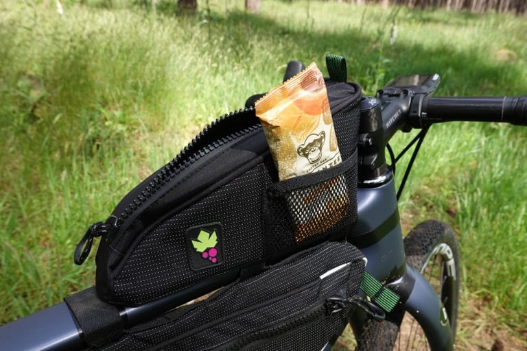 Energy bar tucked into the outer mesh side pocket of the Miss Grape Node 2H top tube bag.