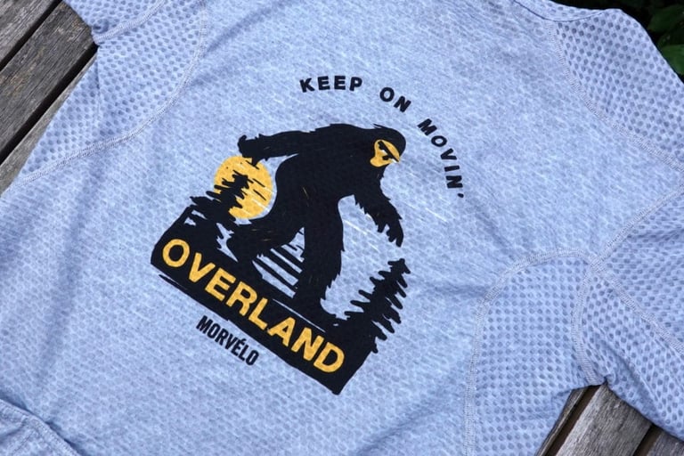 Back print on the Morvelo Dual Baselayer-Jersey of a Bigfoot figure, sun and pines with the slogan Keep on movin'.