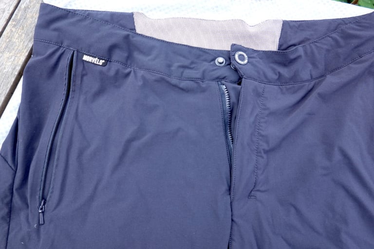 Morvelo Selector shorts laid flat, showing the popper and zip fly, waistband gripper and side zip pocket.