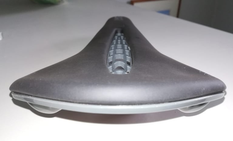 Rear view of the Tioga Undercover Stratum saddle on a table, showing its flat profile and lattice through the cut-out.