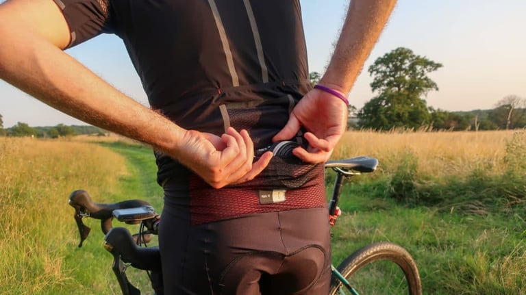 Rider reaching into the large rear mesh pocket of the PEdALED Odyssey bibshorts, below the jersey hem.