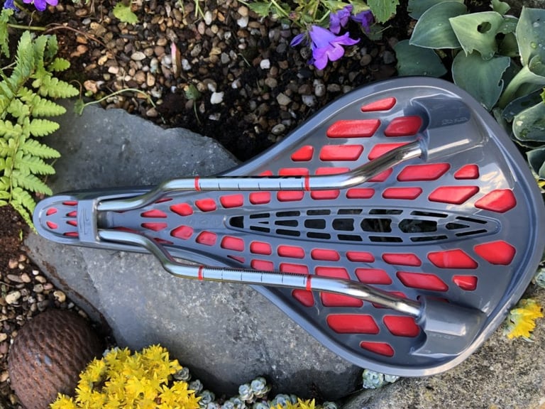 Underside of the Tioga Undercover Stratum saddle, with its red and grey latticework base and metal rails.