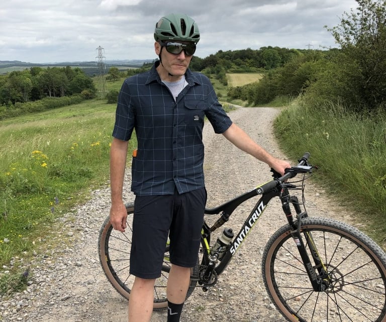 Rider standing beside a Santa Cruz mountain bike on a gravel track in Selector shorts that stop above the knee.
