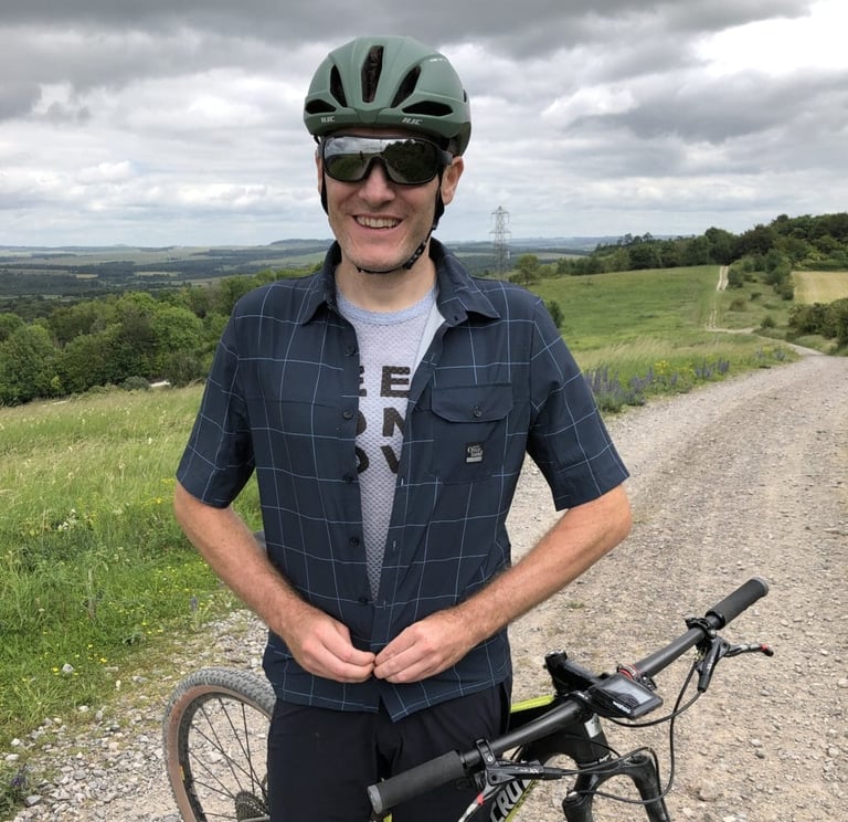 Rider on a gravel track buttoning up the Morvelo Overland short sleeve shirt over a base layer.