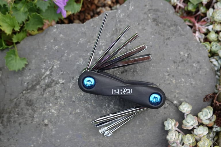 PRO BikeGear Mini Tool 10 multi-tool with hex keys and screwdrivers fanned out on a flat grey stone.
