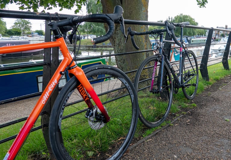 Orange-red All City Zig Zag with Whisky fork in the foreground, the older Mr Pink leaning on the same railing behind.