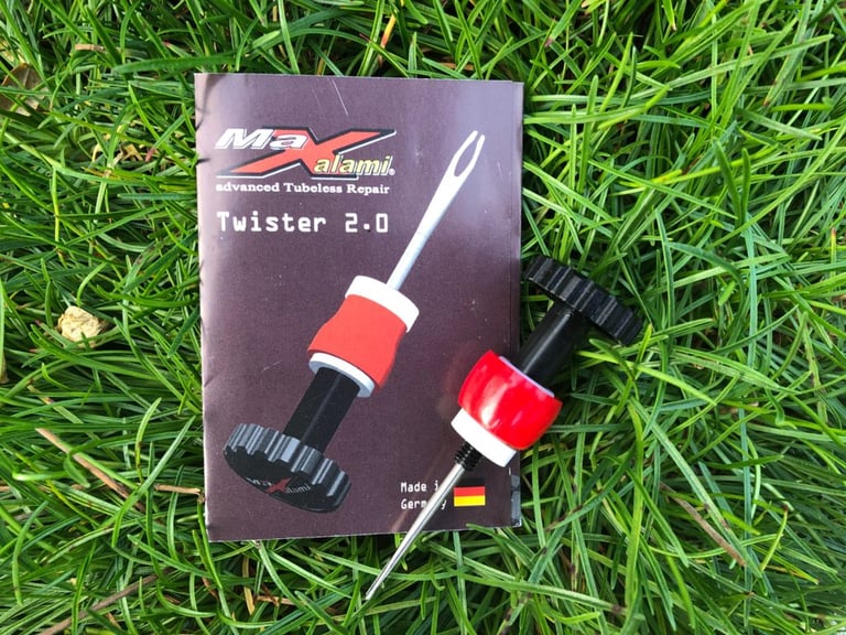 Maxalami Twister 2.0 tubeless repair tool lying on its packet in grass, used to plug punctures on rides.