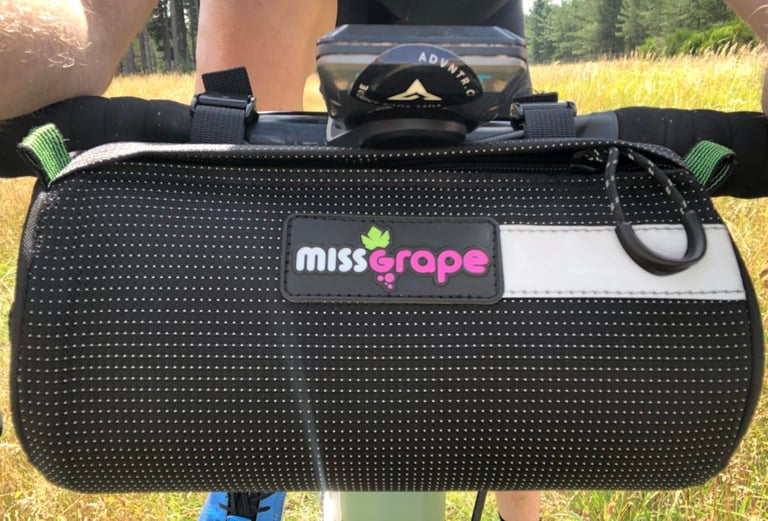 Close view from the saddle of the Miss Grape Moon bar bag's logo patch and wide reflective strip.