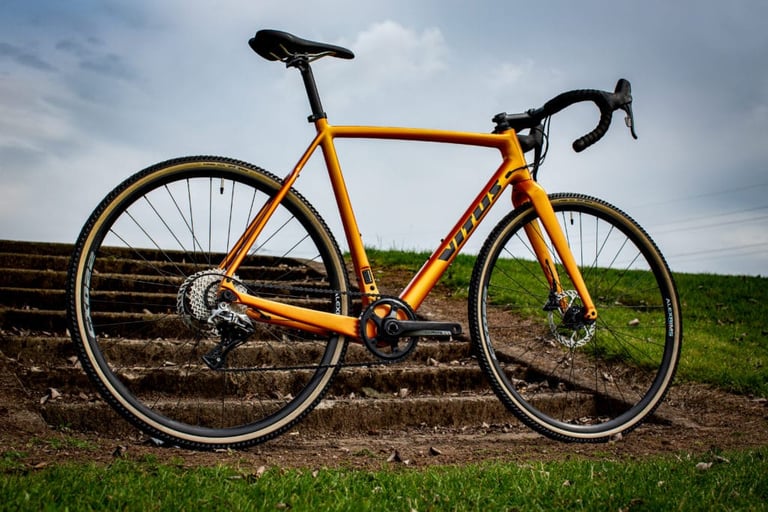 Vitus Energie CR cyclocross bike in orange with a single-ring SRAM Rival 1 set-up, three-quarter view on grass.