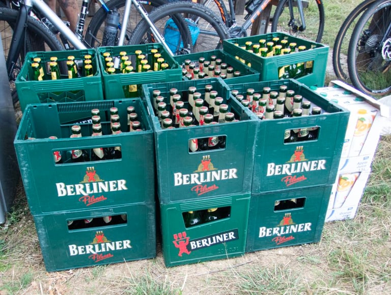 Crates of Berliner Pilsner stacked beside parked bikes at the Pathfinder basecamp.