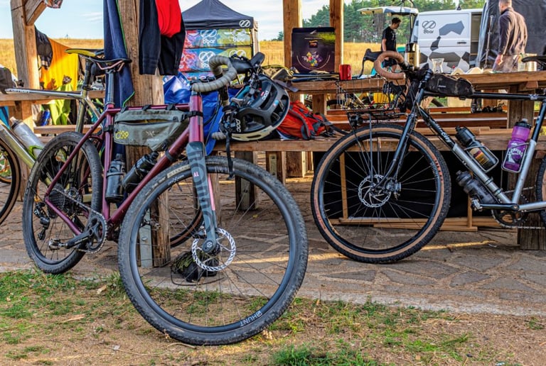 Gravel bikes parked against the wooden shelter at Pathfinder basecamp, with the 8bar van and gazebo behind.