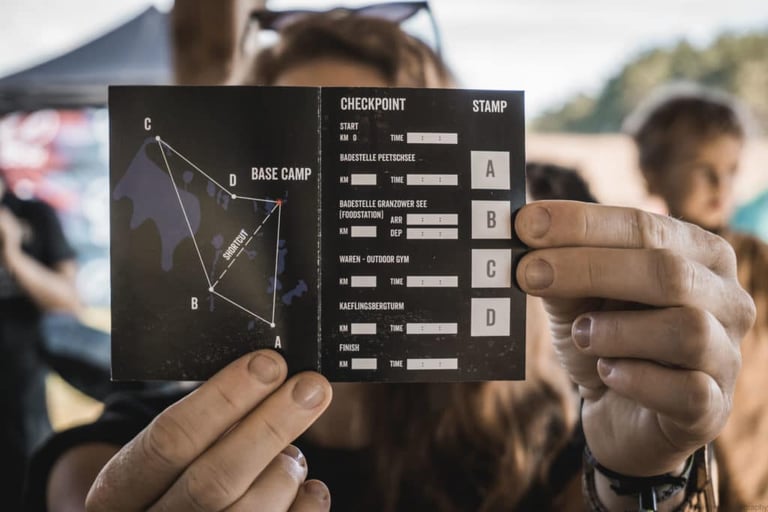 Hands hold up a Pathfinder brevet card with a checkpoint map and stamp boxes A to D.