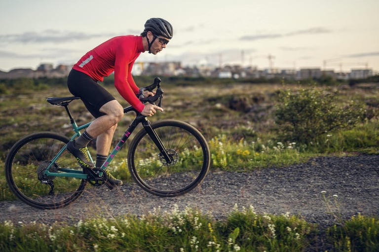 Rider in a red jersey on the carbon Marin Headlands gravel bike on a gravel track at dusk.