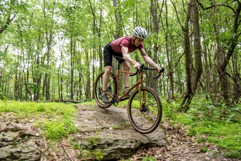 Rider descends a rock slab in woodland on the steel Marin Nicasio with tan-wall tyres.
