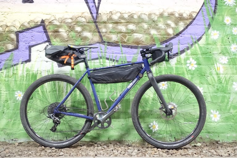 Fairlight Secan gravel bike with a custom Straight Cut frame bag and Ortlieb saddle pack against a painted wall.