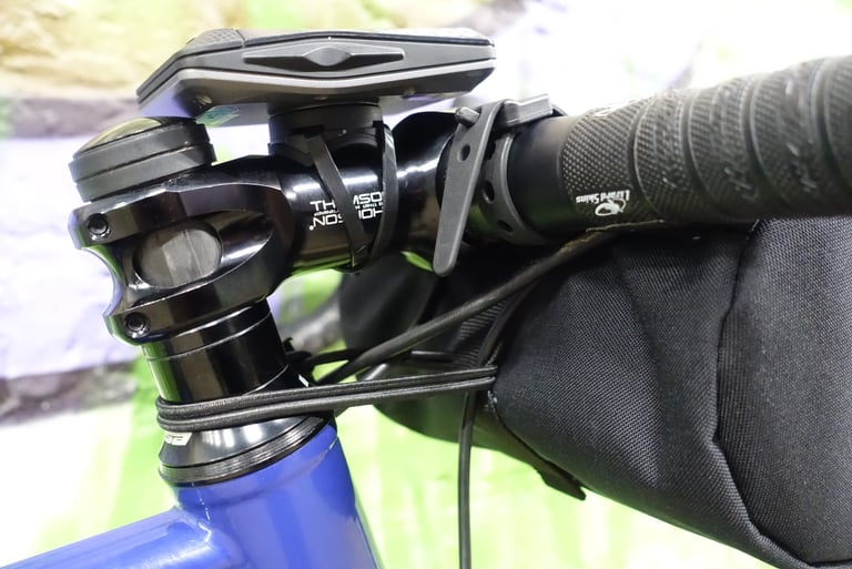 Straight Cut bar bag strapped to a gravel bike's handlebars with Voilé straps and an elastic cord round the head tube.