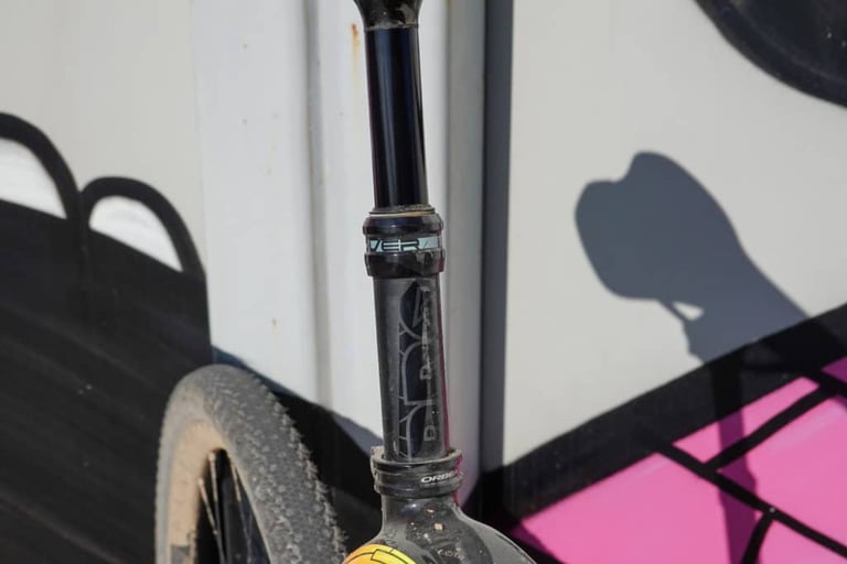 Close-up of the PRO Discover Dropper Post stanchion and seal head, with a gravel tyre behind.