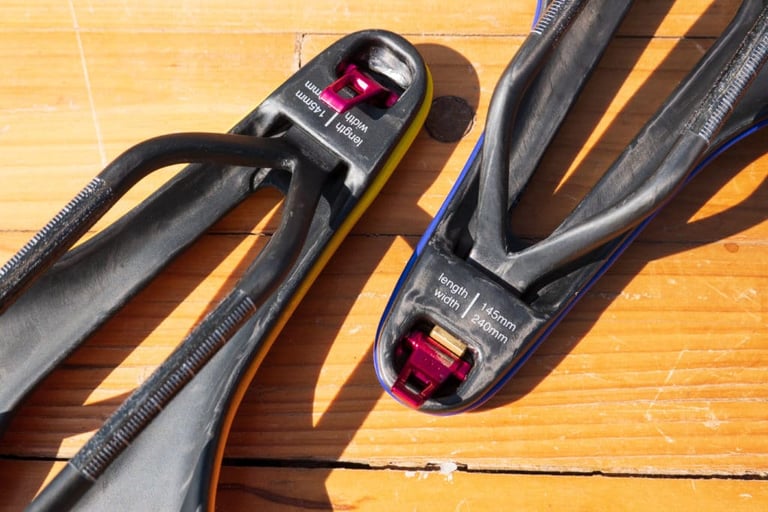 Underside of two ERE Research Genus saddles showing the red Comfort Trigger and 145x240mm size markings.