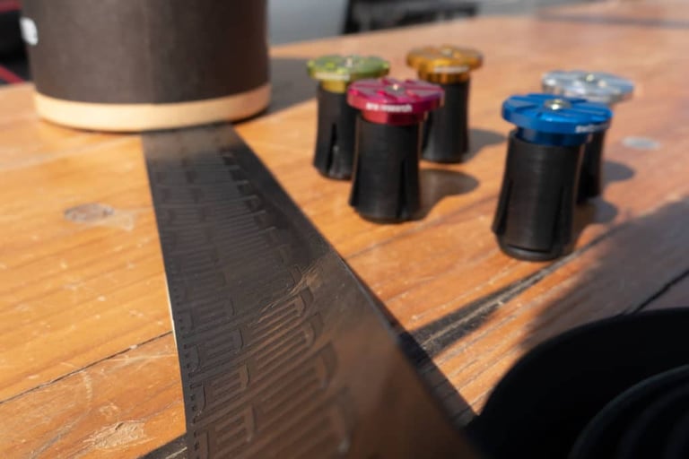 Close view of embossed ERE Research Explorator bar tape with anodised bar end plugs standing behind it.