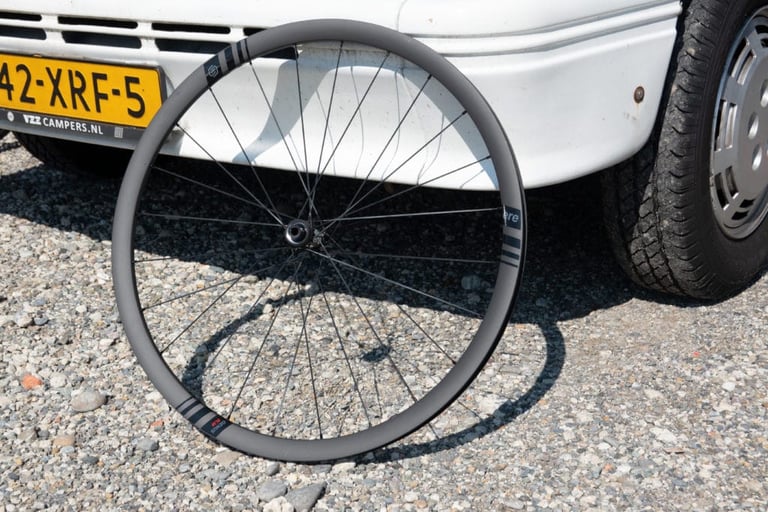 ERE Research carbon front wheel with a shallow rim standing against a Dutch-plated camper van.