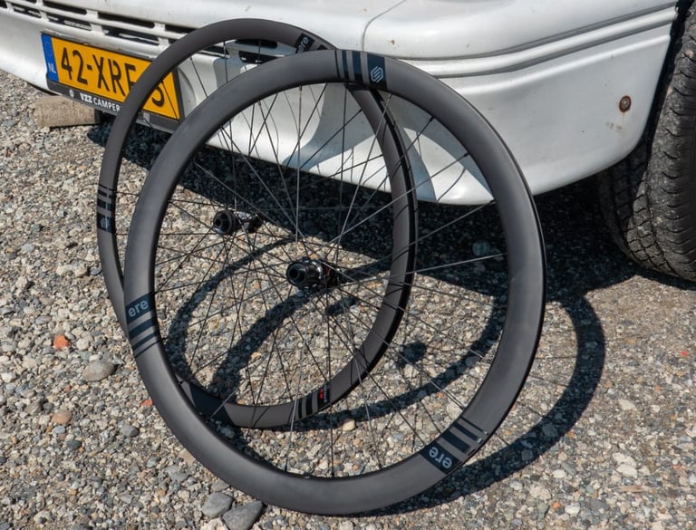 Pair of ERE Research Genus carbon disc-brake wheels propped against a white camper van at Eurobike.