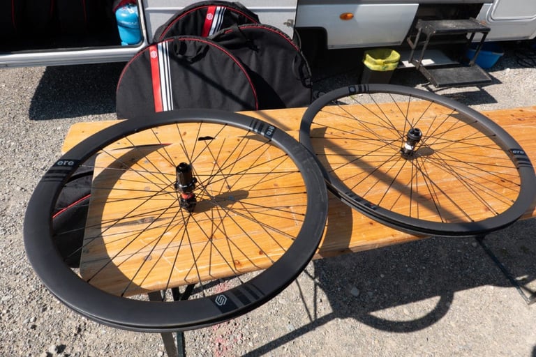 Two ERE Research wheels and their wheel bags laid out on a bench beside Piet's camper van at Eurobike.
