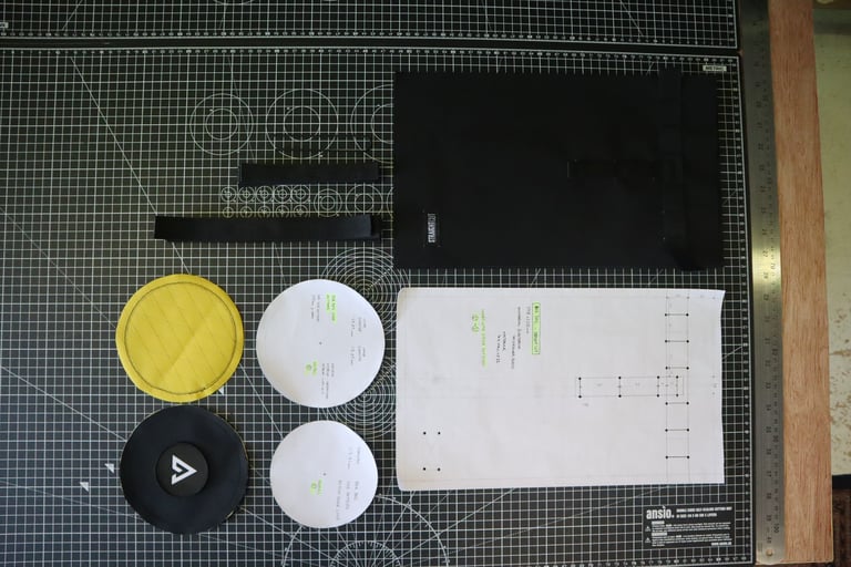 Bar bag pattern pieces on a cutting mat at Straight Cut: yellow and black discs, webbing straps and paper templates.