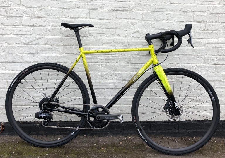 Nate's 17lb All-City Macho King build with SRAM Force AXS and DT Swiss carbon wheels against a white brick wall.