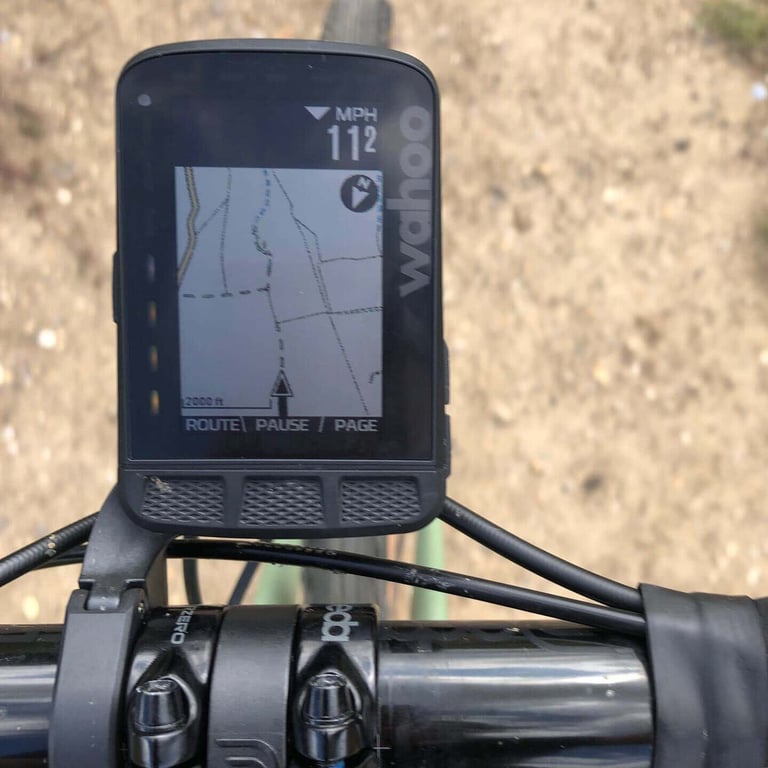 ELEMNT ROAM map view with a dashed route line and thin trail lines, mounted on a bike's handlebars.