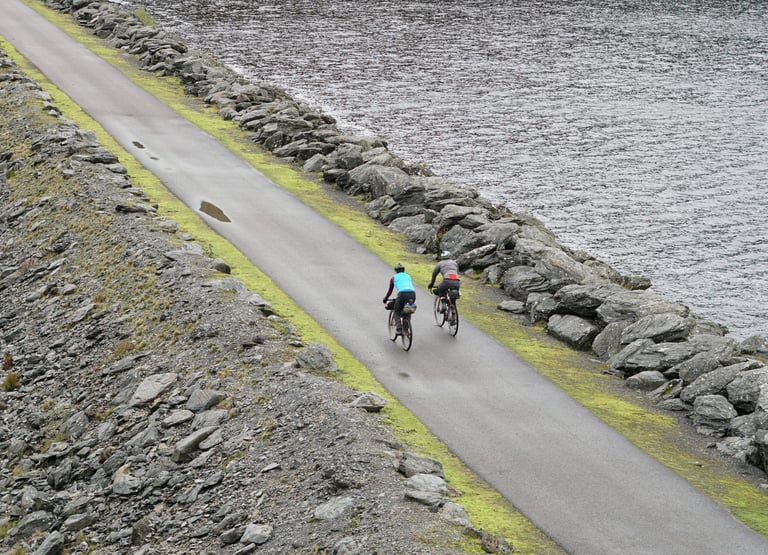 Two bikepacking riders cross the Llyn Brianne dam on the Wildcat 100 route in Mid Wales.