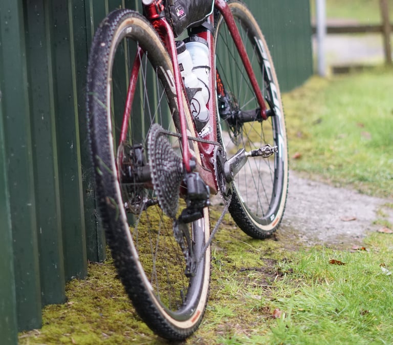 Rear wheel of a muddy Cervelo Aspero showing the wide-range cassette of its SRAM Mullet build.