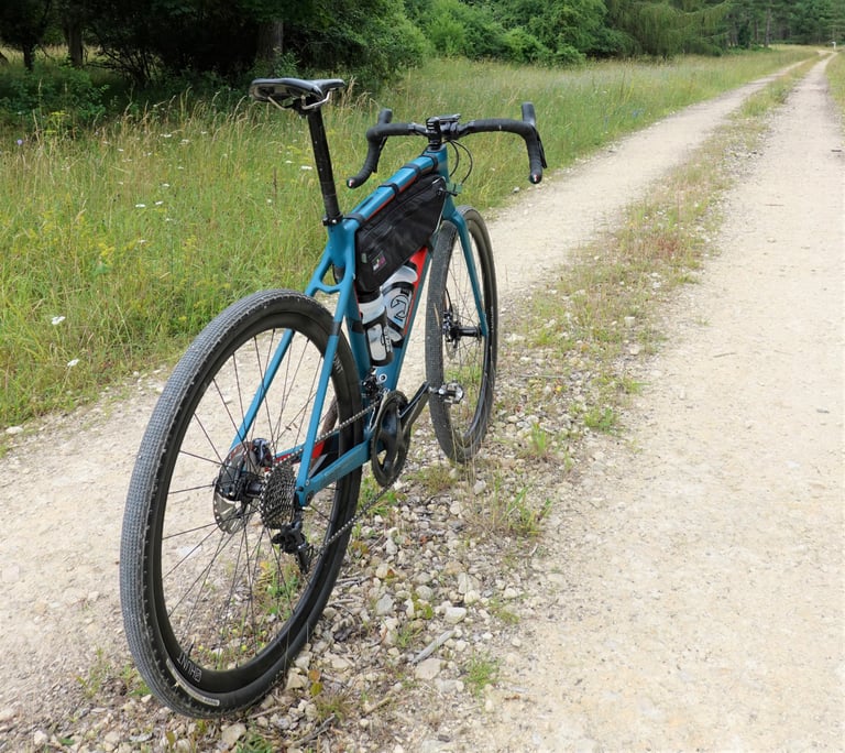 Rear three-quarter view of the Wilier Jena showing thin, flattened seatstays and a frame bag on a gravel track.