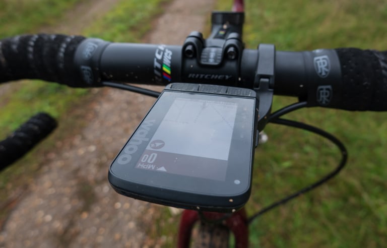 Wahoo ELEMNT ROAM on an out-front mount under a Ritchey WCS handlebar, seen from the saddle on a grassy track.