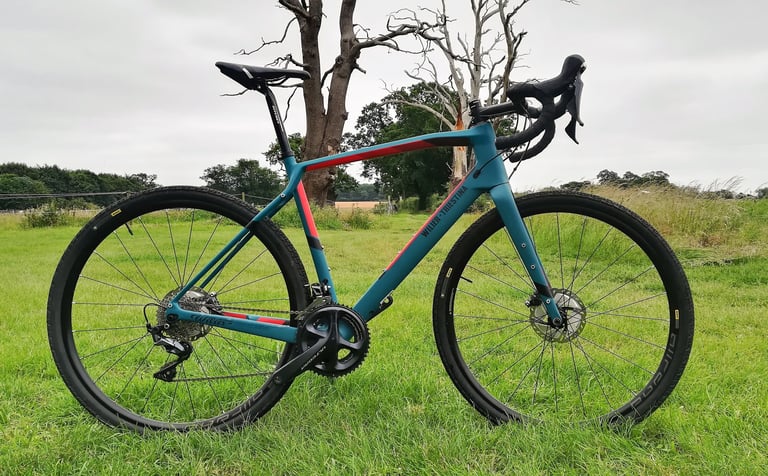 Wilier Jena in teal and red with Shimano Ultegra and Mavic Allroad 700c wheels, side view on grass.