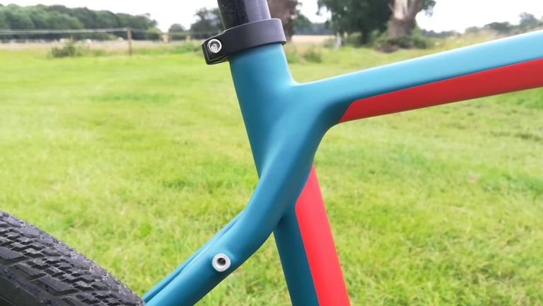 Wilier Jena seat tube junction with curved seatstays, a mudguard mount and seat clamp, in teal with red stripe.