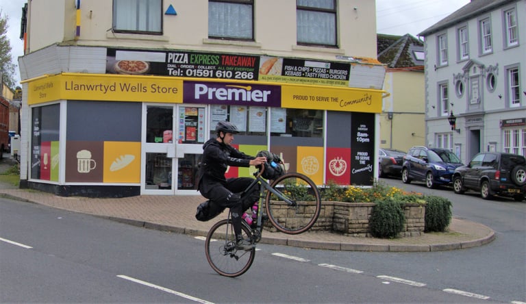 James Heaton of WTB wheelies a loaded Trek Crockett past the Premier store in Llanwrtyd Wells on the Wildcat 100.