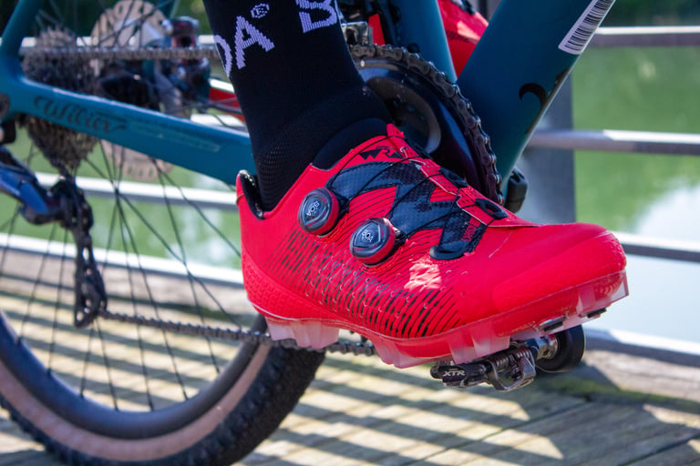 Neon red Suplest Cross Country Pro shoe clipped into a Shimano XTR pedal on a teal Wilier bike.